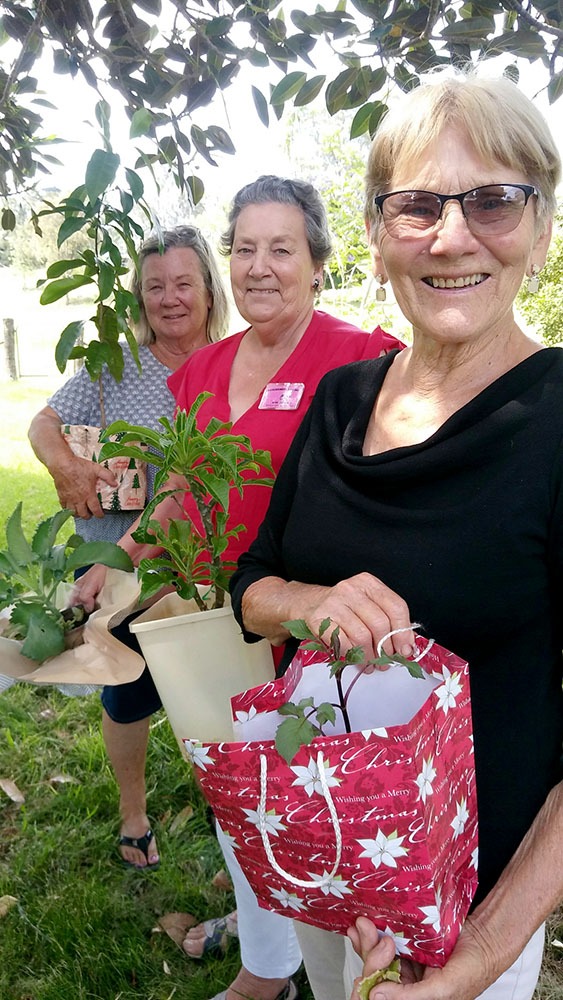 Three very happy gardeners with their new plants: (L to R) Robyn O’Donnell with a native orange berry plant; Bev Must with an evergreen frangipani; and Shirley Schwarz with a red dahlia