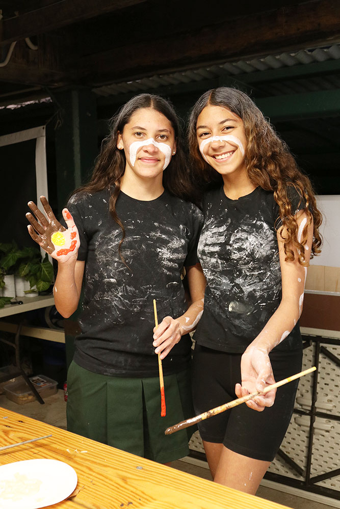 Jimbelungaree Dumunn Dance Troop performers, Kyara and Chenoa,  paint their hands for the Community Hand Print Banner